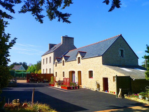 A stone building with a steep roof, a chimney, and a gated entrance. - 800m from beaches, GR34 and Ménéham classified site. 4 people.enclosed garden (Kerlouan)