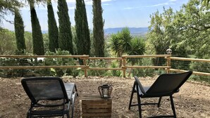 An outdoor seating area with two black chairs and a wooden crate, surrounded by a wooden fence and cacti.