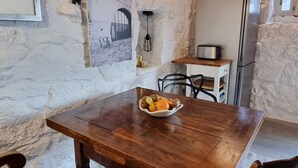 Une cuisine rustique avec une table et des chaises en bois, ainsi qu’un mur en pierre.