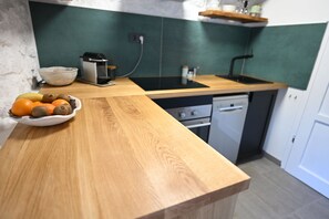Una cocina con encimera de madera, un cuenco de fruta, un lavabo y un lavavajillas.