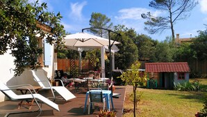 Une terrasse dotée de mobilier d’extérieur, d’un espace salon couvert et d’un petit abri de jardin.