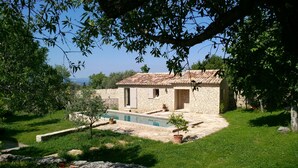 A stone house with a tiled roof, a swimming pool, and a garden with grass and trees. - Air-conditioned detached house with a pool, on a family-owned property (Gordes)