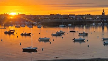 Un port au coucher du soleil, avec des bateaux et une vue sur la ville en arrière-plan.