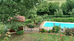 Una piscina rodeada de exuberante vegetación, una estructura de madera y un jardín bien cuidado.