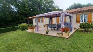 Una casa con porche cubierto, mobiliario exterior y plantas en macetas.