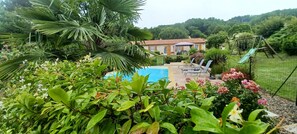 Ein Pool, umgeben von üppiger Vegetation, mit einem Haus im Hintergrund.