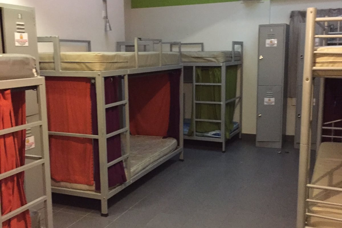 A dormitory room with bunk beds, a green wall, and a tiled floor.
