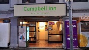 L’entrée d’une auberge de jeunesse, avec une enseigne indiquant : « Campbell Inn Hostel Lounge ».