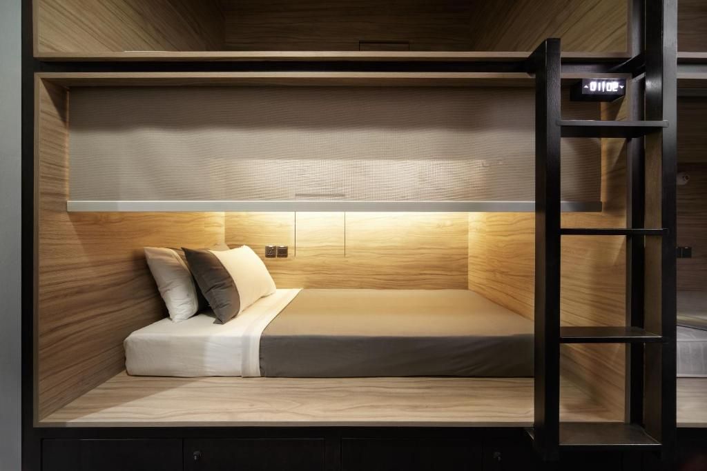 Un lit superposé avec une tête de lit, une table de chevet et une horloge numérique.