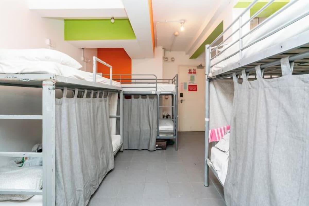 Habitación tipo dormitorio con literas, una pared de acento verde y una puerta con un letrero rojo.