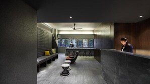 A modern interior with a reception desk, seating area, and a view through a window. - Campbell Inn - Hostel (Singapore)
