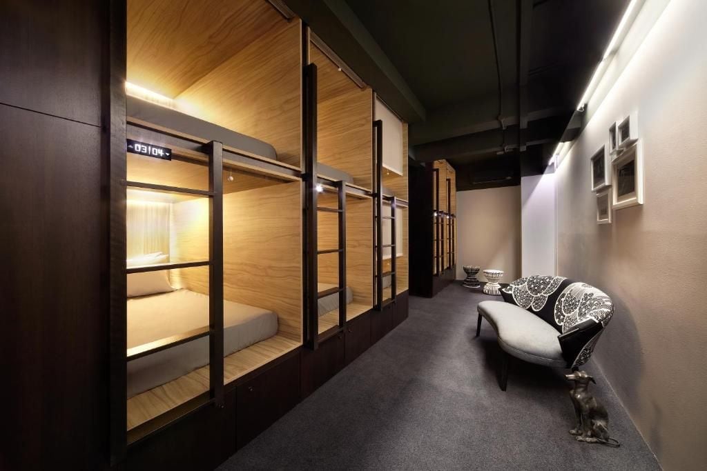 A hallway with bunk beds and a bench with a decorative cushion.
