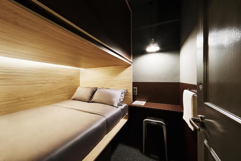 Ein kleines Zimmer mit einem Bett, einem Schreibtisch und einer Tür.