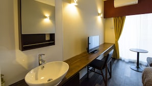 Uma casa de banho de hotel moderna com uma grande pia, espelho e uma televisão de ecrã plano sobre um balcão de madeira.