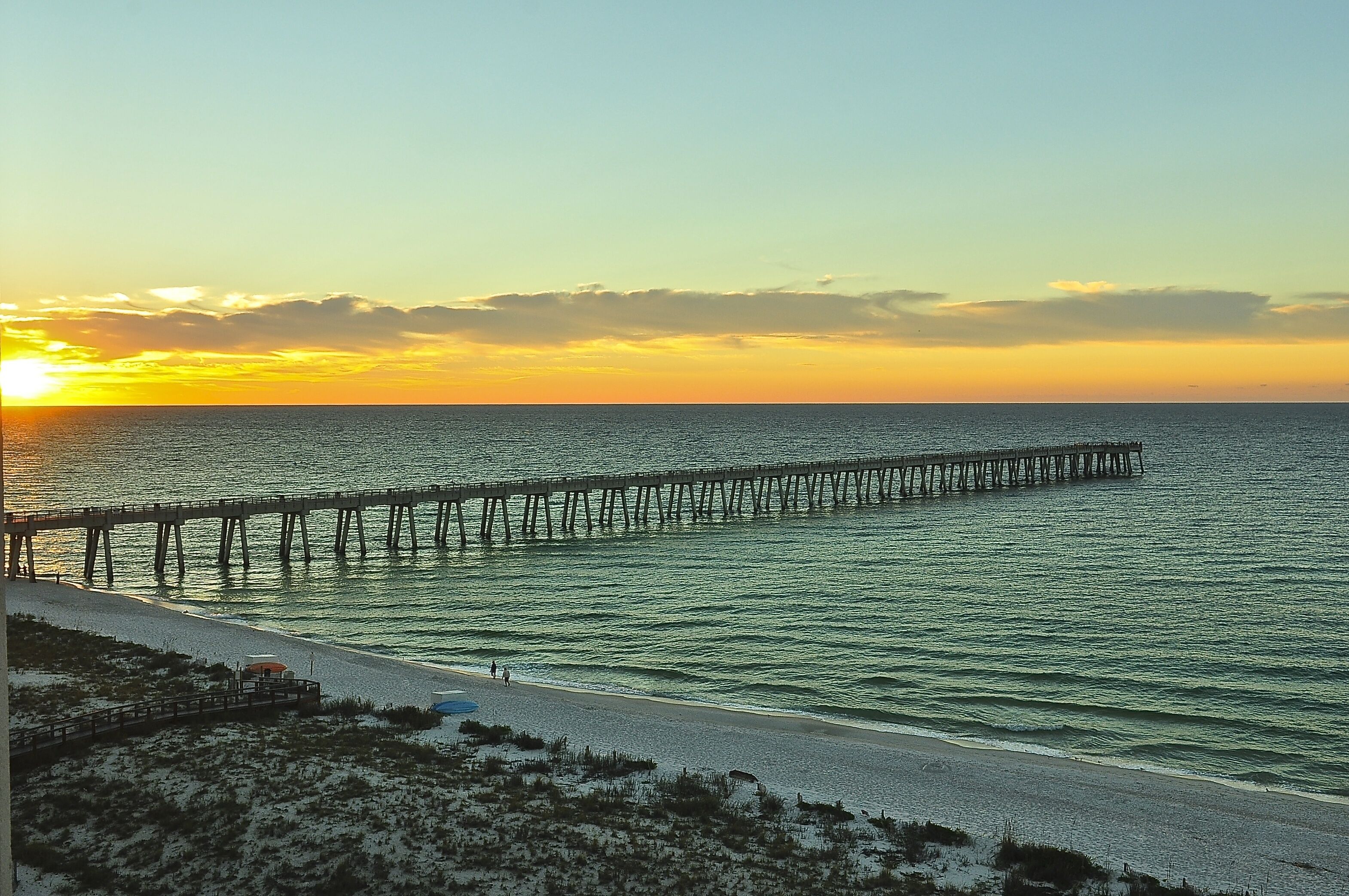A pier extending into the ocean at sunset.