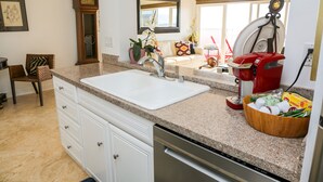 A kitchen with a granite countertop, white cabinets, a coffee maker, and a bowl of snacks. - Stunning Multimillion Dollar Whitewater -interior by Artist- special 2026 prices (Dana Point)