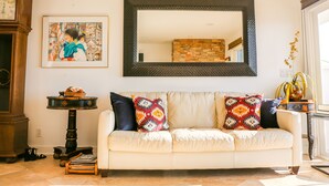 A living room with a beige sofa, a large mirror, a clock, and a framed picture on the wall. - Stunning Multimillion Dollar Whitewater -interior by Artist- special 2026 prices (Dana Point)