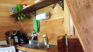 A wooden kitchen with a stove, microwave, sink, and various kitchen utensils. - The Lily Pad, headwaters of Eden Falls (Ponca)