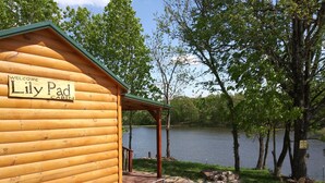 A wooden cabin named 'Lily Pad Cabin' with a view of a lake and surrounding trees. - The Lily Pad, headwaters of Eden Falls (Ponca)