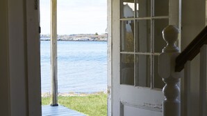Une porte en bois qui donne sur un porche offrant une vue sur un plan d’eau.