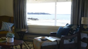 Un salon chaleureux avec vue sur la mer, comprenant un canapé, une table basse et un tapis à motifs.
