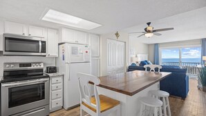 Une cuisine moderne avec des meubles blancs, des appareils en acier inoxydable et un îlot central en bois doté de tabourets de bar.