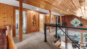 Interior de madera con una escalera que conduce a un balcón.