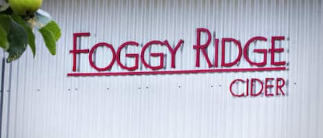 Una pared de metal corrugado con el texto 'Foggy Ridge Cider' en letras rojas.