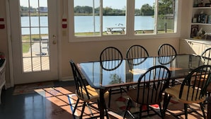 A dining area with a glass table and chairs, large windows with a lake view, and a door with a 'Great Catch' sign.