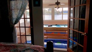 A room with a bed, a view of a pool, and a ceiling fan.