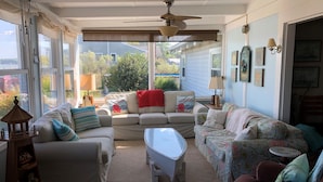 A living room with a sofa, armchairs, a coffee table, and a ceiling fan.