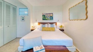 Un dormitorio con cama, mesita de noche, espejo y ventana con persianas.