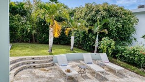 Un área de piscina con sillones de descanso y una terraza de piedra.