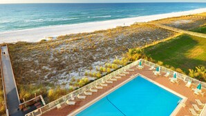 A beachside hotel with a pool, lounge chairs, and a view of the ocean.