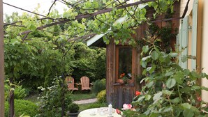 Ein Holzhaus mit Garten, einem Tisch mit Tischdecke und zwei Adirondack-Stühlen.