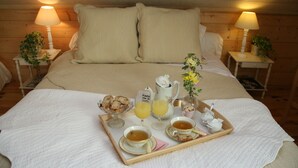 Ein ordentlich bezogenes Bett mit einem Tablett mit Frühstücksartikeln, darunter Toast, Tee und Saft.