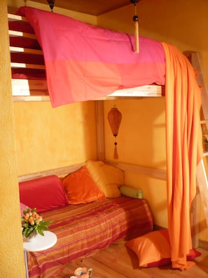 Ein gemütliches Zimmer mit einem Etagenbett, einem kleinen Tisch mit Blumenvase und einer Wandleiter.