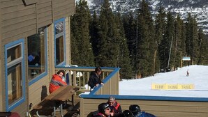 Un bâtiment en bois doté d’un balcon donnant sur un paysage montagneux enneigé.