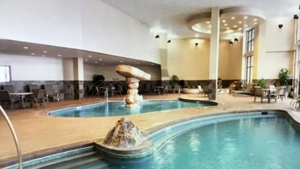 Une piscine intérieure dotée d’une fontaine centrale, entourée d’espaces de détente et de coins salon.