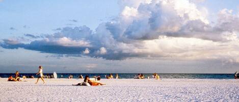 A beach with people sunbathing and walking.