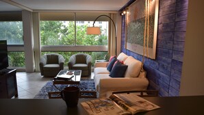 Una sala de estar moderna con un sofá, sillones, una mesa de centro y un televisor.