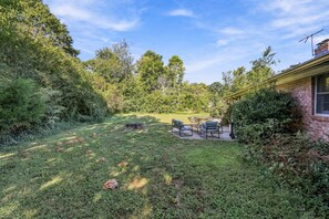 A backyard with a patio area, a wooden deck, and a brick house.