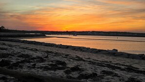 Une plage avec un rivage rocheux et un coucher de soleil en arrière-plan.