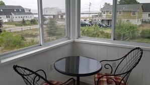 Une pièce d’angle avec une fenêtre donnant sur un quartier résidentiel, une petite table ronde et deux chaises.
