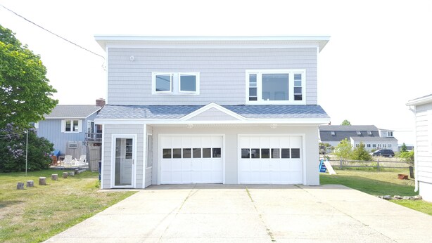 Une maison à deux étages avec un garage, une porte d’entrée et un petit porche.