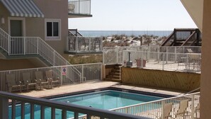 Uma área de piscina com vista para a praia, uma escadaria e um corrimão.
