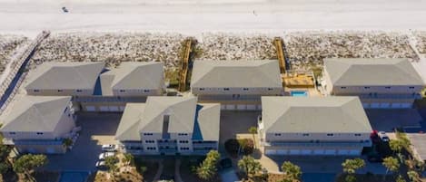 A beachfront hotel with multiple buildings, a sandy beach, and a pier.
