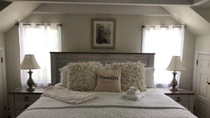 A bedroom with a large bed, two nightstands, a headboard with a floral pillow, and a painting on the wall. - Country farmhouse !!! (Sinking Spring)