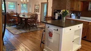 A kitchen with wooden cabinets, a brick fireplace, and a dining area with a wooden table and chairs. - Country farmhouse !!! (Sinking Spring)