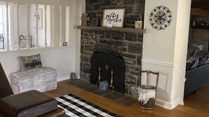 A living room with a stone fireplace, a black and white checkered rug, and a white railing. - Country farmhouse !!! (Sinking Spring)